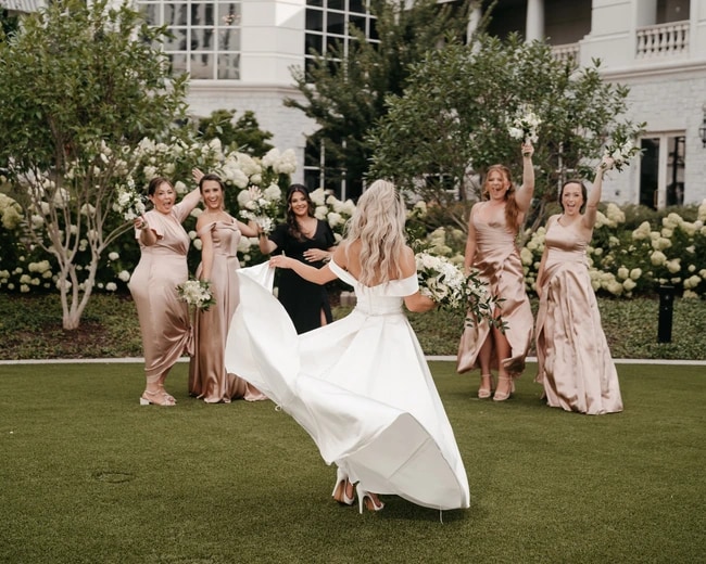 Bride twirling in her gown surrounded by her bridesmaids