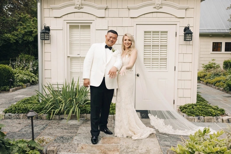 Outdoor wedding ceremony aisle with white chairs and floral arrangements
