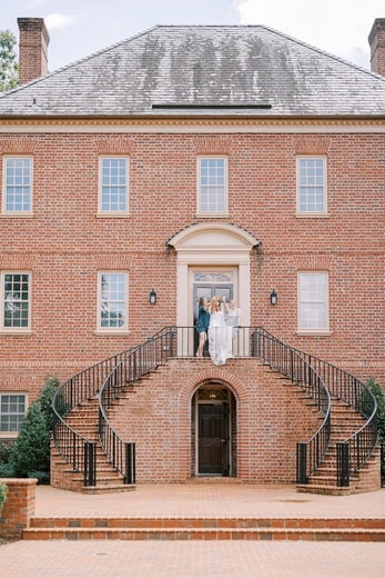 Bride and friends toasting on a grand brick mansion staircase