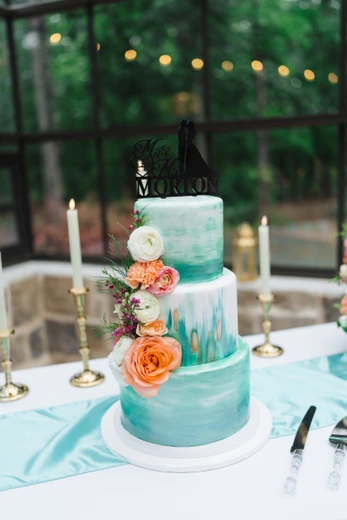 Three-tier teal watercolor wedding cake with florals