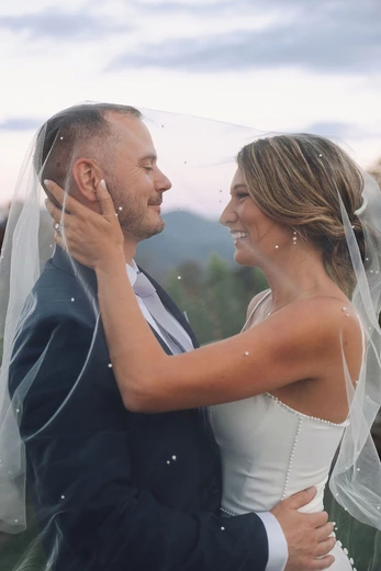 Bride and groom embracing under a pearl-trimmed veil