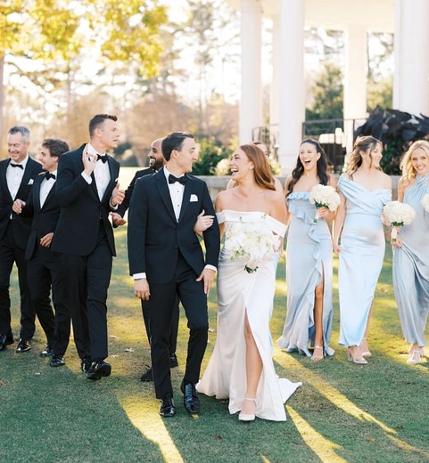 Wedding party walking together across a green lawn