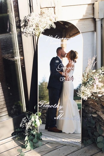 Arched welcome mirror sign with florals at a wedding